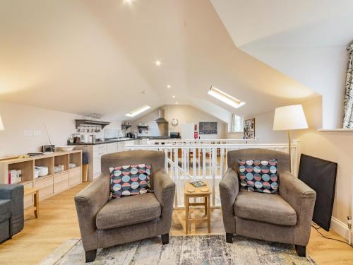 a living room with two chairs and a kitchen at The Stables At Wells-In-The-Field Farm in Whitchurch