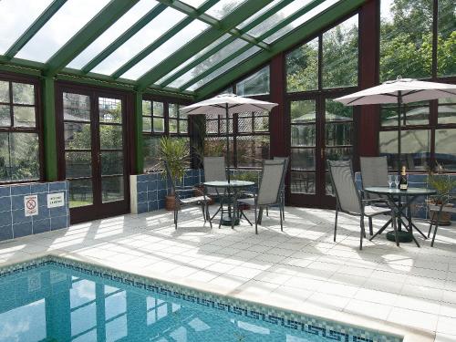 a conservatory with a pool and tables and umbrellas at St Andrews Barn in Necton