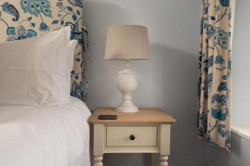 eine Lampe auf einem Nachttisch neben einem Bett in der Unterkunft Weavers Cottage in Stow on the Wold