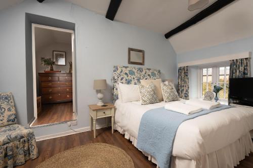 a bedroom with a bed and a chair and a television at Weavers Cottage in Stow on the Wold