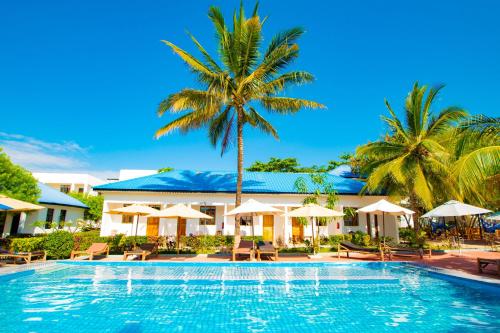 een zwembad in een resort met palmbomen en parasols bij Severini Villas Zanzibar in Nungwi