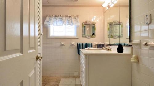 Un baño blanco con lavabo y espejo. en Escape To Yacht - Upstairs Apartment, en Cape May