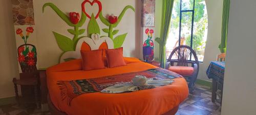 a bedroom with an orange bed with flowers on the wall at HOSTAL PIEDRA ANDINA - Copacabana in Copacabana