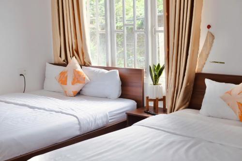 une chambre avec deux lits et une fenêtre dans l'établissement Vân Nhi MTV Hotel, à Đà Lạt