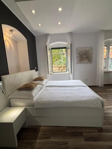 a bedroom with a large white bed and a window at Studio Apartman Fictilis in Split