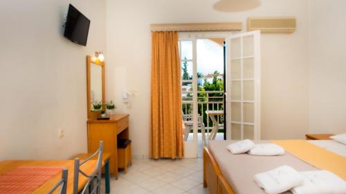 a room with two beds and a table with a mirror at Olga Studios - 1 in Tsilivi