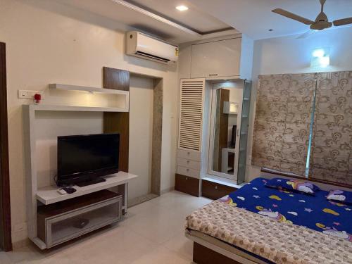 ein Schlafzimmer mit einem Bett und einem Flachbildfernseher in der Unterkunft 4 BHK Duplex Flat at Baner, Pune in Pune