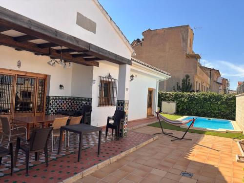 ラス・ガビアスにあるSueños De La Vegaのテーブルと椅子とプールのあるパティオ