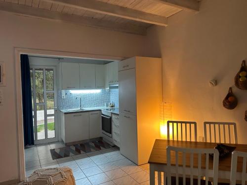 a kitchen with white cabinets and a table and a dining room at Ostria spiti in Aígio