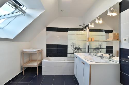 Le Vau PiardにあるLes 9 plages - Piscine privéeの洗面台2つとバスタブ付きのバスルーム