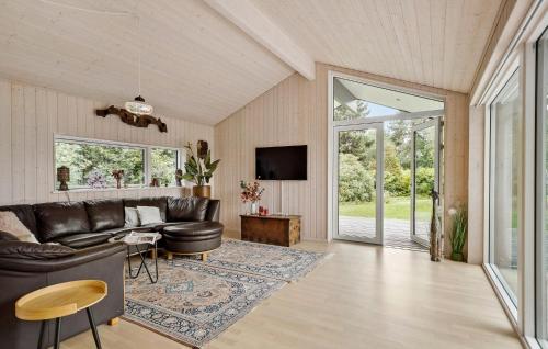 a living room with a leather couch and a tv at Nice Home In Dronningmølle With Sauna in Firhøj