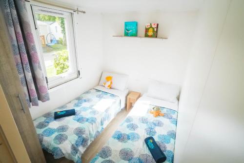 ein kleines Zimmer mit zwei Betten und einem Fenster in der Unterkunft Happy Camp mobile homes in Villaggio Camping Baia Domizia in Baia Domizia
