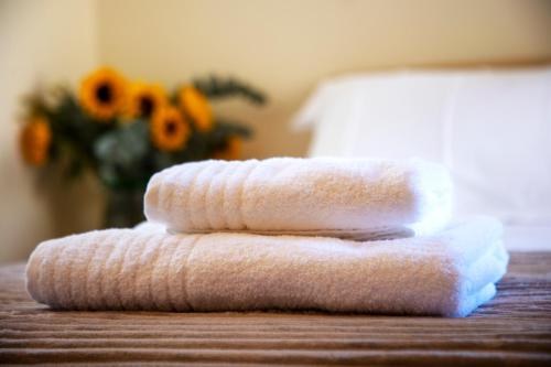three towels stacked on a table with a vase of flowers at Vista Mare Aegina in Kipséli