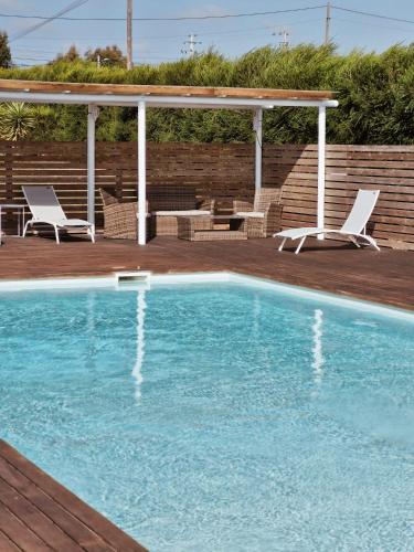 a swimming pool with two chairs and a gazebo at Casa Amarela in Zambujeira do Mar