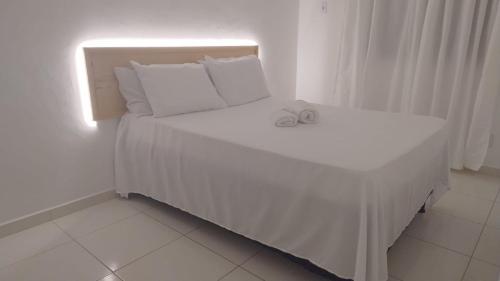 a bed with white sheets and pillows in a room at Grande Aracaju ap executivo in São Cristóvão