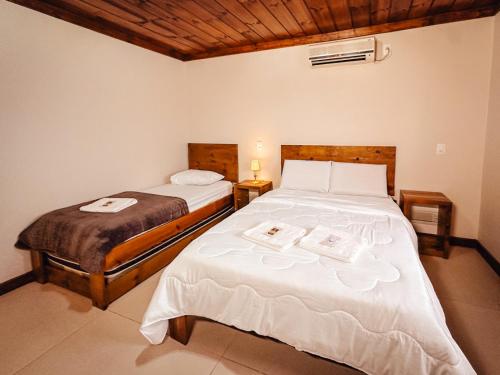 a bedroom with two beds with white sheets at Pousada Charm Canela in Canela