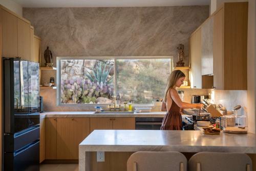 een vrouw die eten bereidt in een keuken met een raam bij La Grange by The CoHost Company in Rimrock