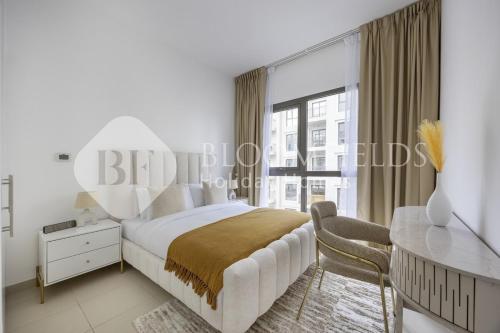 a bedroom with a bed and a desk and a window at Bloomfields Cozy 1br Apt Town Square in Dubai