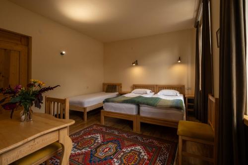 a bedroom with two beds and a table and a rug at Saryan Guesthouse in Goris
