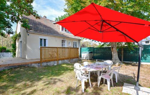 a table and chairs with a red umbrella in a yard at 3 Bedroom Awesome Home In Cabourg in Cabourg