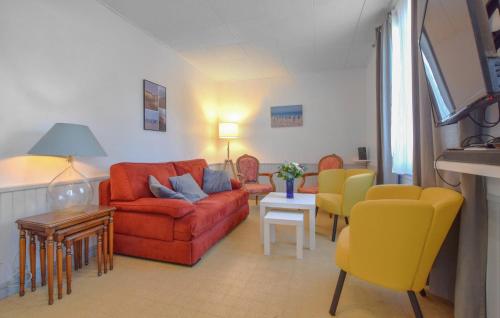 a living room with a red couch and yellow chairs at 3 Bedroom Awesome Home In Cabourg in Cabourg