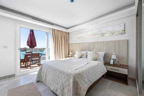 a bedroom with a white bed and a balcony at The sunset resorts - منتجع ساحل الغروب in Jeddah