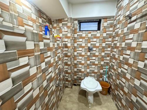 een badkamer met een toilet in een kamer met tegels bij City Nest Studio in Agartala