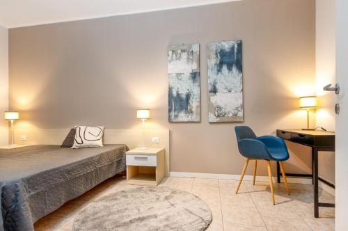 a bedroom with a bed and a desk and a blue chair at HB Appartamenti in centro Bergamo in Bergamo