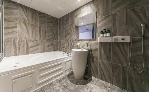 a bathroom with a tub and a sink at Nampo MGM Hotel in Busan