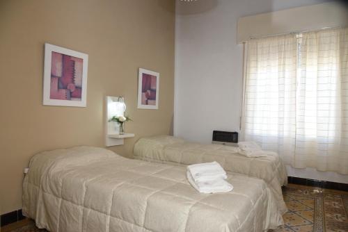 two beds in a hotel room with towels on them at Altos Yrigoyen Hotel in Marcos Juárez