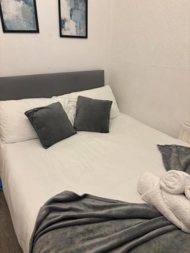 a white bed with black pillows and a towel on it at Cosy Spacious Studio Flat,N18 in London