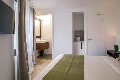 een slaapkamer met een bed en een badkamer met een wastafel bij La Chasse 5 in Brussel