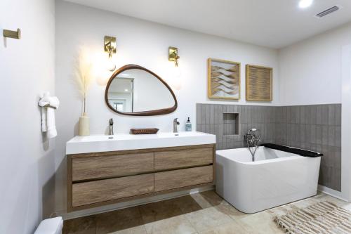 a bathroom with a tub and a sink and a mirror at Group Retreat Fairhope in Fairhope