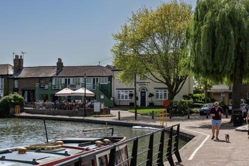 a man walking next to a river with a boat at Riverside Inn in Ely