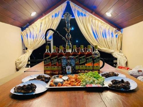 a table with a tray of food and bottles of wine at Hill Paradise in Nuwara Eliya