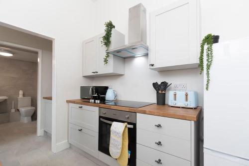 une cuisine avec des armoires blanches et un comptoir dans l'établissement Spacious 3BR • WiFi • Parking • Contractor Stay, à Monkwearmouth