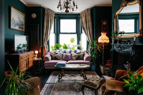 a living room with a pink couch and a table at Bohemian Retreat by the Sea with wood burner, roll-top bath & leafy garden in Margate