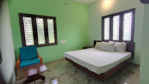 a bedroom with a bed and a blue chair at Aruna homes -Lakshana- Thanjavur in Thanjāvūr