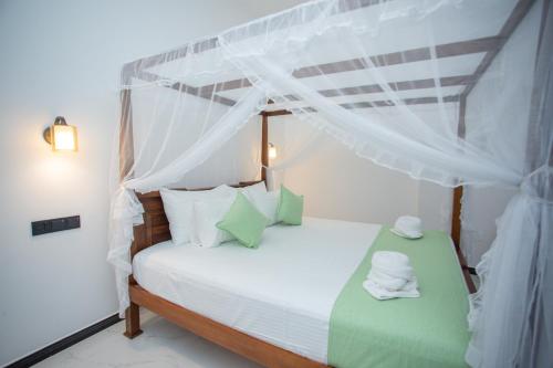 a bedroom with a canopy bed with towels on it at Villa Claudia Nimal's kitchen in Ahangama