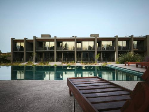 a building with a swimming pool in front of it at Vistalba Hotel Aparts & Suites in Ciudad Lujan de Cuyo