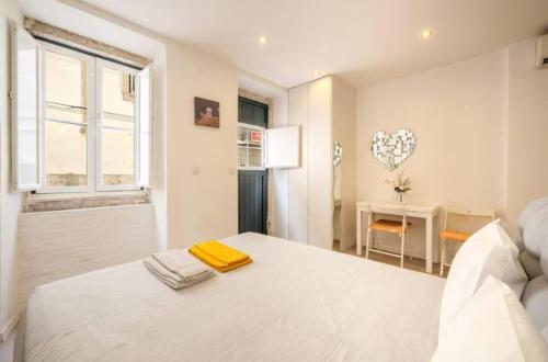 a white bedroom with a bed and a window at Typical Lisbon center in Lisbon