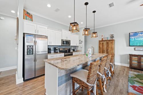 a kitchen with a large counter with chairs and a refrigerator at Latitudes ‘N Attitudes in Gulf Shores