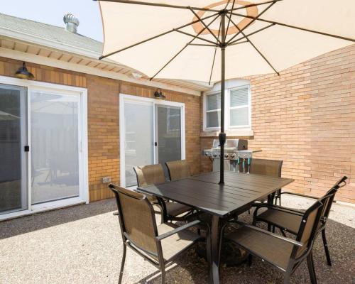 a wooden table with an umbrella on a patio at Riggs House Restored 1908 Home in Maquoketa