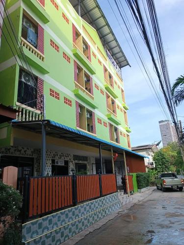 a yellow and green building with a car parked in front at Natcha Place Klongluang 35 in Ban Bang Khan