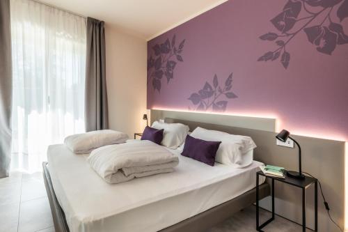 a bedroom with a bed with white sheets and purple walls at Holiday Apartments Campoverde in Salò