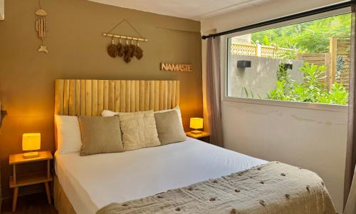 een slaapkamer met een bed en een groot raam bij Koho SXM - ex Hevea Hotel in Grand Case