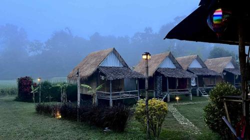 a group of houses with lights in the grass at Sparrow Hut in Pai