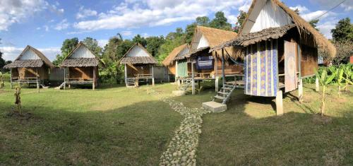 a group of huts in a field with a path at Sparrow Hut in Pai