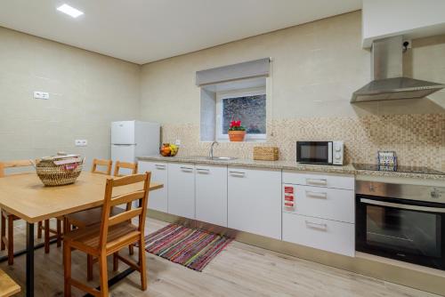 a kitchen with white cabinets and a wooden table at Rustic & Modern Stone House by Host Wise in Pedroso