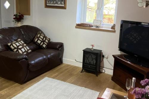 a living room with a leather couch and a television at Little Owls Nest - 2 Bed - Pet Friendly w Field in Wisbech